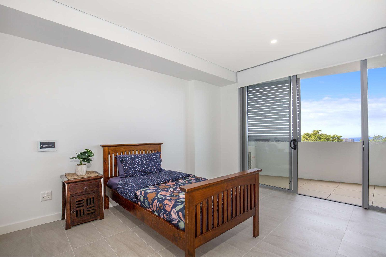 Photo 4 of 10: Bedroom with a timber bed and sliding doors to a balcony