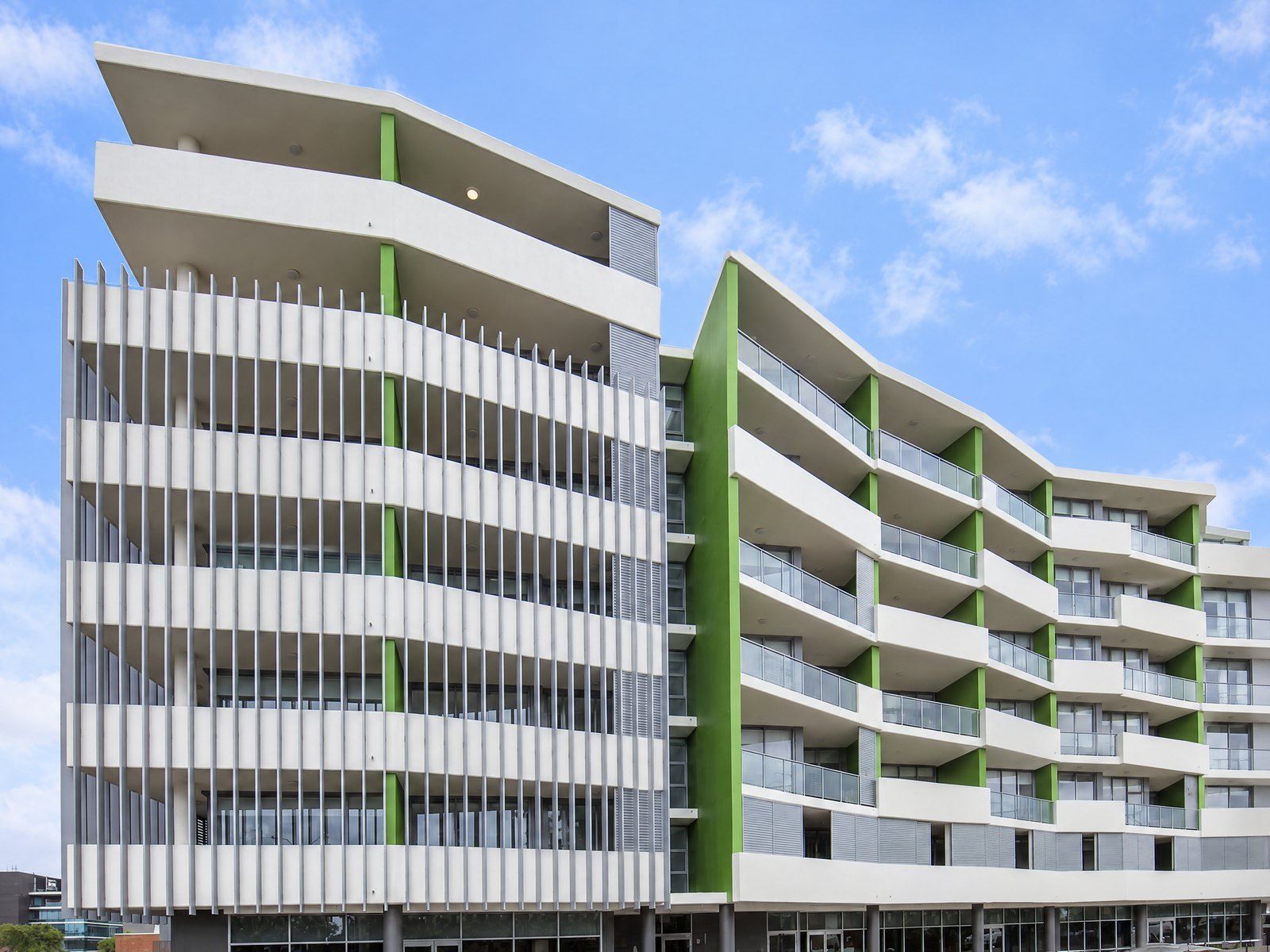 Modern six-level apartment building in Wollongong, with white balconies and green feature walls against a blue sky